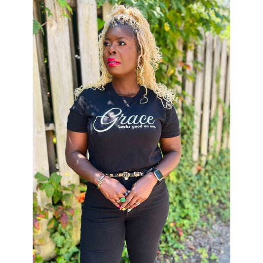 Woman styling Black Grace Looks Good On Me tee outdoors with casual accessories