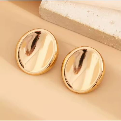 Flatlay of gold button stud earrings displayed on neutral-toned surface