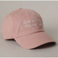 Pink cap with 'God is Good All the Time' text on a beige background