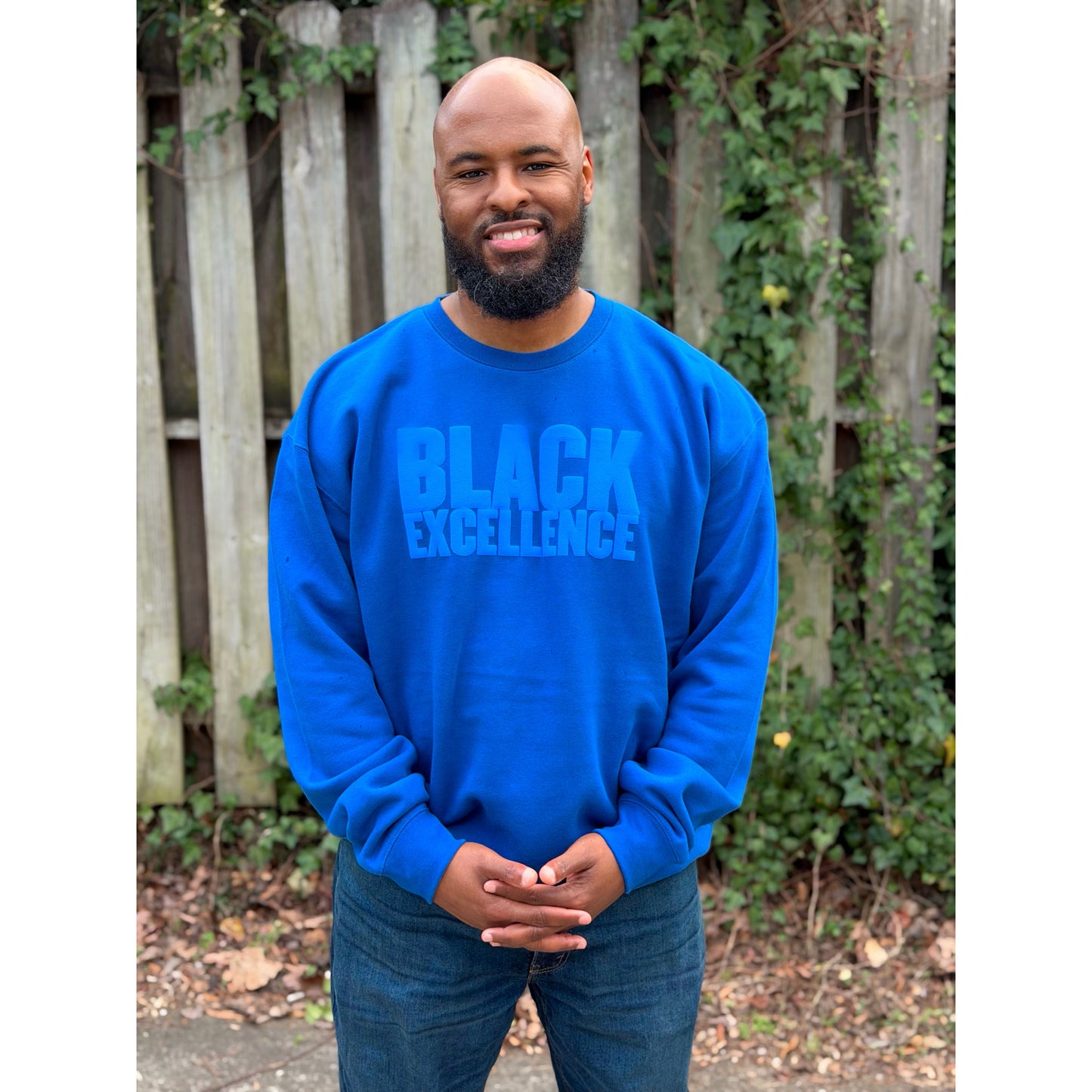 Man modeling a royal blue sweatshirt featuring the "Black excellence" design in puff print.