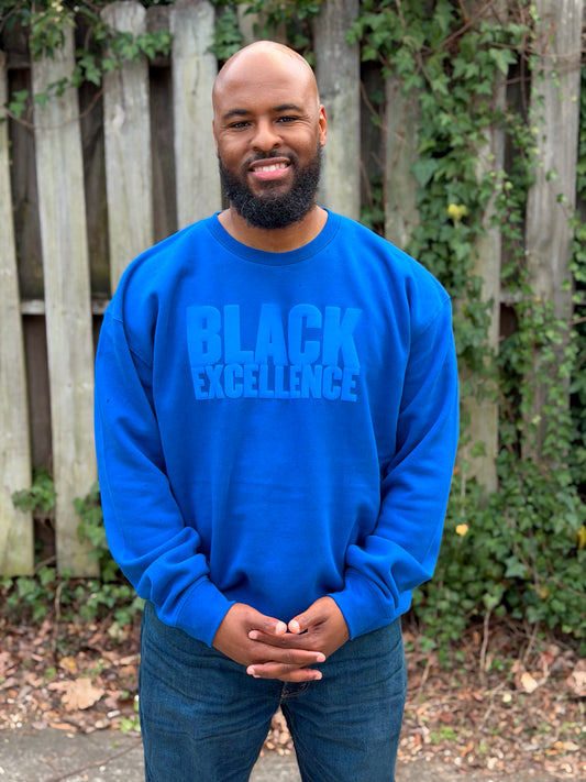 Man modeling a royal blue sweatshirt featuring the "Black excellence" design in puff print.