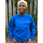 Model wearing a royal blue sweatshirt featuring the “Pray, Manifest, Work, Succeed, Repeat” design in puff print.