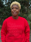 Model wearing a red sweatshirt featuring the “Pray, Manifest, Work, Succeed, Repeat” design in puff print.
