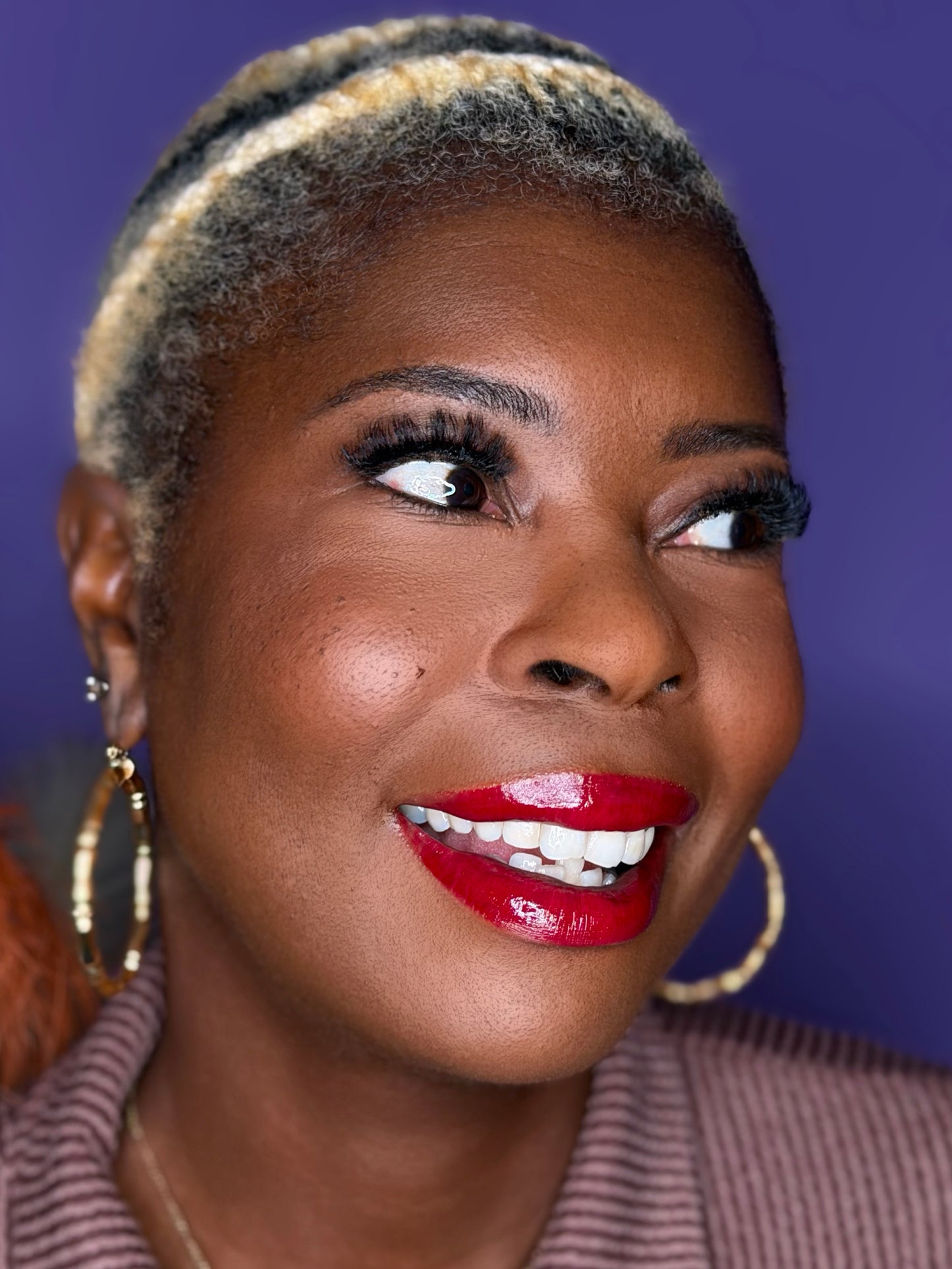 Woman with styled hair and red lipstick against a purple background wearing c-curl lash Sapphire