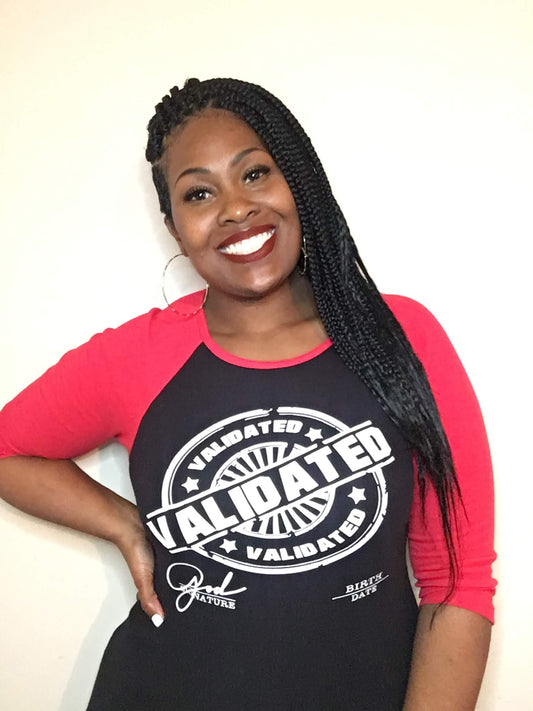 Black woman smiling in a black and red raglan tee featuring the bold white “Validated” stamp design across the chest. Tee has red three-quarter sleeves and a fitted unisex cut.