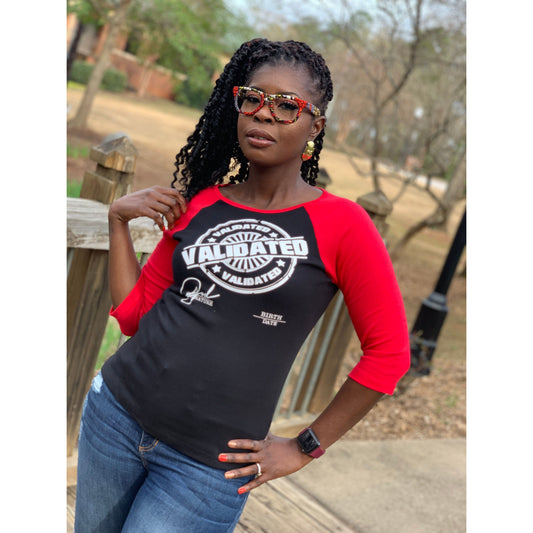 Black woman smiling in a black and red raglan tee featuring the bold white “Validated” stamp design across the chest. Tee has red three-quarter sleeves and a fitted unisex cut.