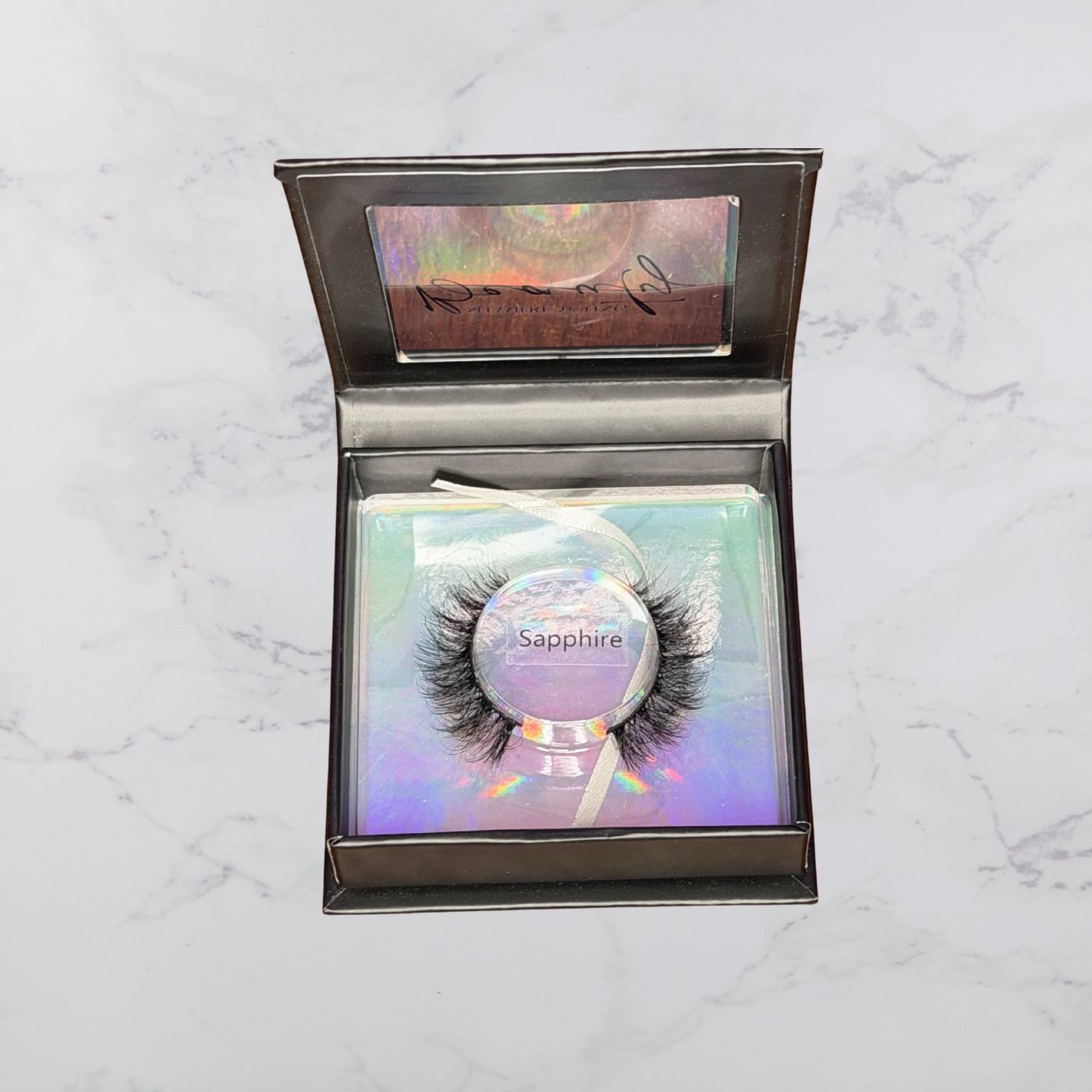 Eyelash packaging with 'Sapphire' label on a marble surface