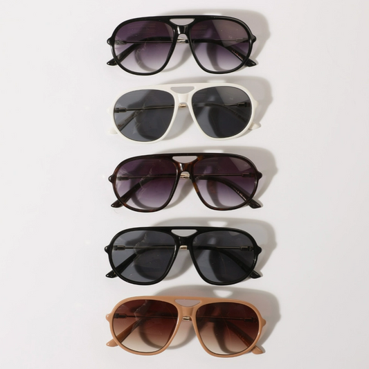 Five pairs of sunglasses stacked on a white background