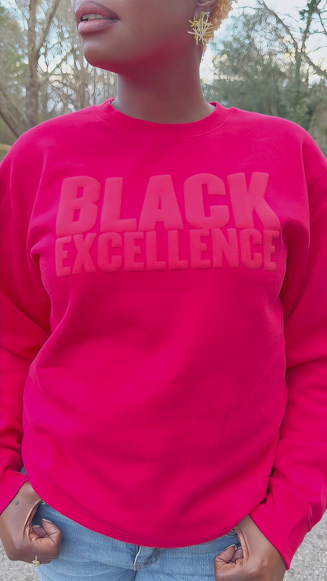 Woman modeling a red sweatshirt featuring the "Black excellence" design in puff print.